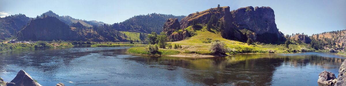 A river bending past sunlit cliffs and pine-covered hills in Montana